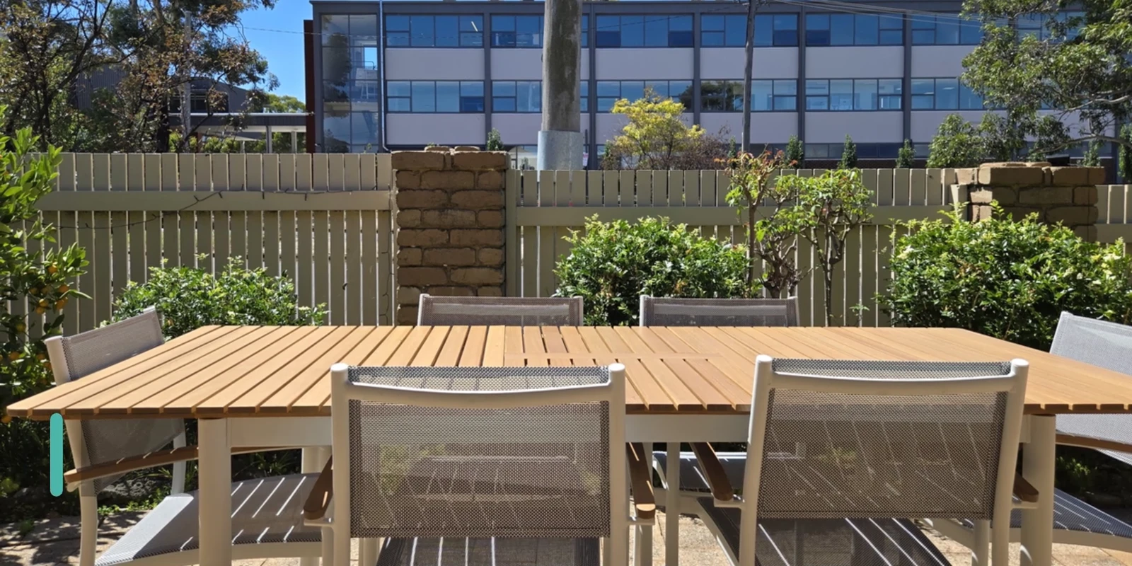 Outdoor dining area at the Ryrie Street residence with a timber table, chairs and planted garden beds